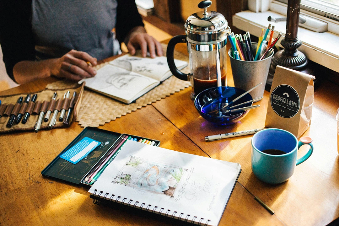 person sketching with coffee at a cozy cafe windsor.